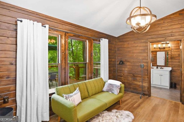 sitting room with light wood-type flooring, lofted ceiling, and wooden walls