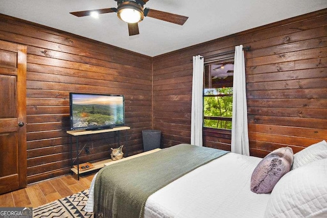 bedroom with ceiling fan, hardwood / wood-style floors, and wooden walls