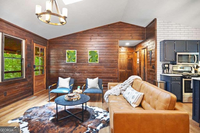 living room with light wood-type flooring, lofted ceiling, a chandelier, and wooden walls