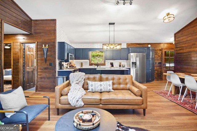 living room featuring lofted ceiling, light wood-type flooring, and sink