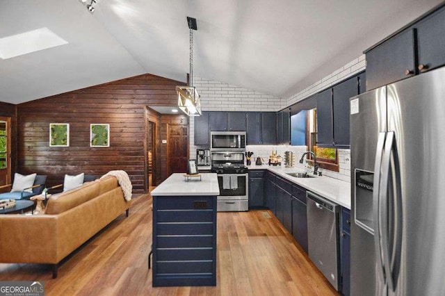 kitchen featuring a kitchen island, stainless steel appliances, hanging light fixtures, light wood-type flooring, and lofted ceiling with skylight