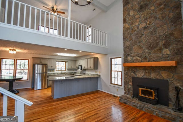 kitchen with high vaulted ceiling, kitchen peninsula, gray cabinets, and stainless steel appliances