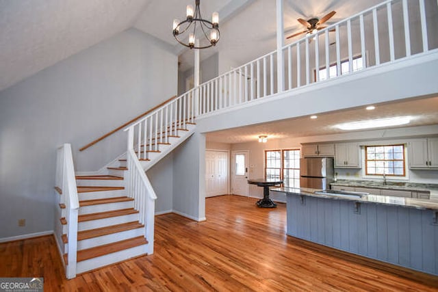 kitchen with a healthy amount of sunlight, light hardwood / wood-style flooring, stainless steel fridge, and high vaulted ceiling