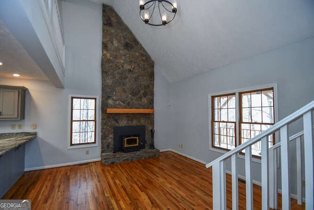 unfurnished living room featuring dark wood-type flooring, a chandelier, lofted ceiling, and a fireplace