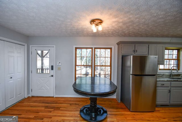 kitchen featuring a textured ceiling, sink, gray cabinetry, and stainless steel refrigerator