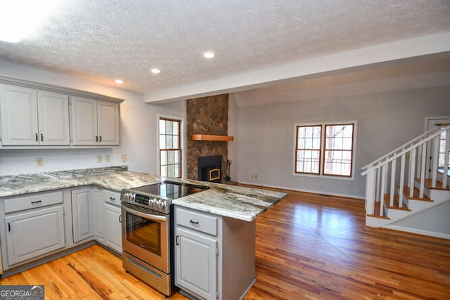 kitchen with kitchen peninsula, gray cabinetry, a textured ceiling, and stainless steel range with electric stovetop