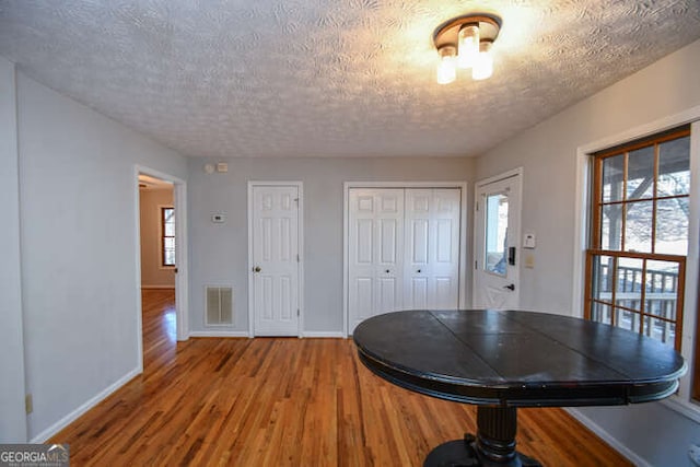 dining room with a textured ceiling, a healthy amount of sunlight, and hardwood / wood-style flooring