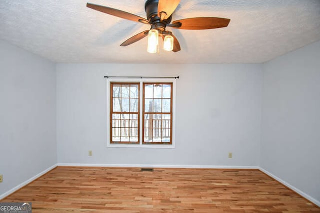 empty room featuring ceiling fan, light wood-type flooring, and a textured ceiling