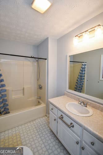 bathroom featuring a textured ceiling, shower / bath combo, and vanity