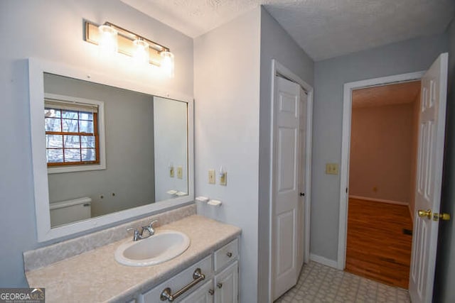 bathroom featuring a textured ceiling, toilet, and vanity