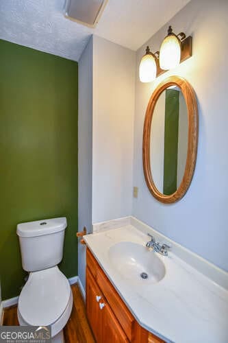 bathroom with toilet, vanity, wood-type flooring, and a textured ceiling