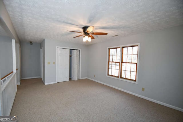 unfurnished bedroom with ceiling fan, a textured ceiling, and light carpet