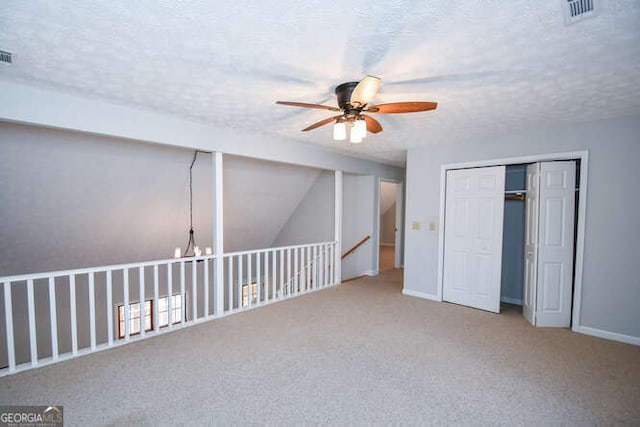 interior space with ceiling fan, a textured ceiling, and carpet flooring