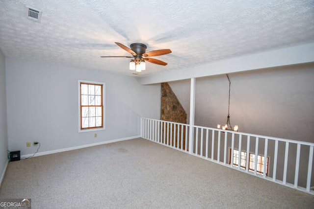 carpeted spare room featuring a textured ceiling and ceiling fan with notable chandelier