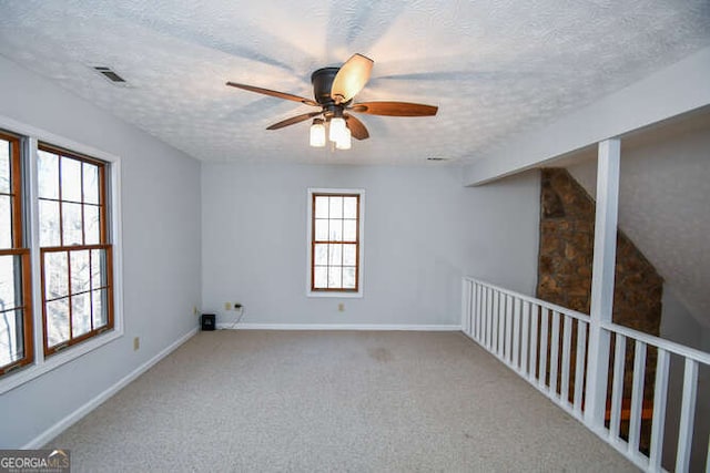 carpeted spare room featuring ceiling fan and a textured ceiling