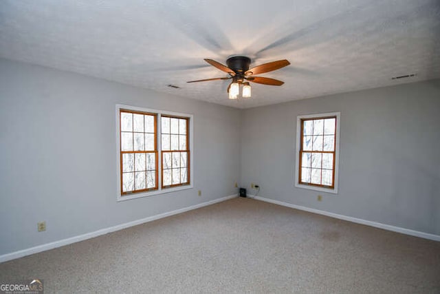 carpeted spare room featuring ceiling fan and a wealth of natural light