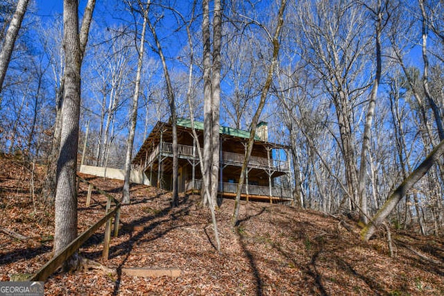 rear view of house featuring a balcony and a wooden deck