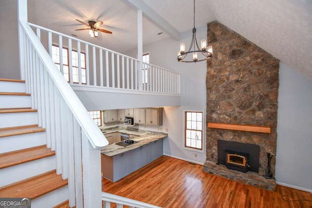 kitchen featuring a high ceiling, ceiling fan with notable chandelier, beam ceiling, and hardwood / wood-style flooring