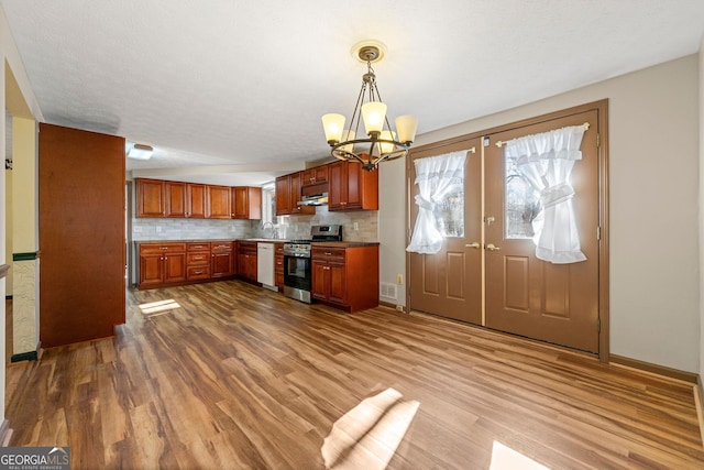 kitchen featuring sink, white dishwasher, tasteful backsplash, stainless steel range, and decorative light fixtures