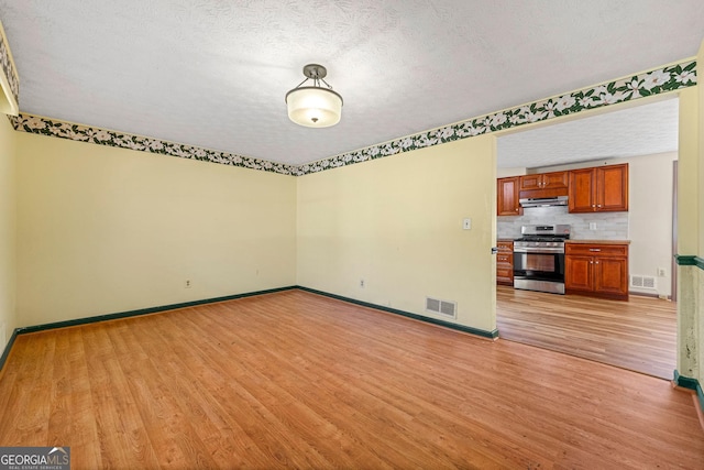 unfurnished living room featuring a textured ceiling and light wood-type flooring