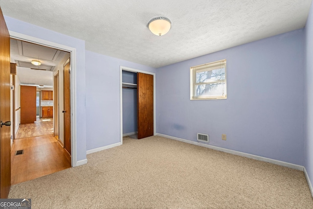 unfurnished bedroom featuring carpet flooring, a closet, and a textured ceiling