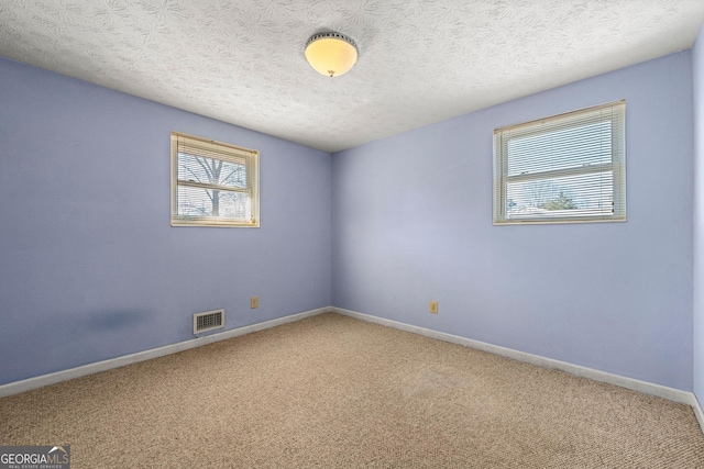 carpeted empty room with a textured ceiling