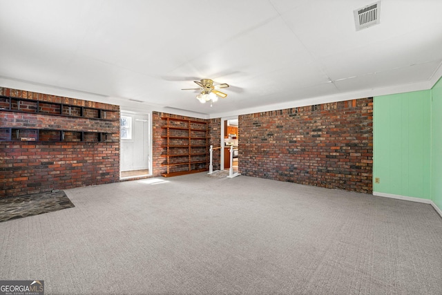 unfurnished living room featuring carpet floors, ceiling fan, and brick wall