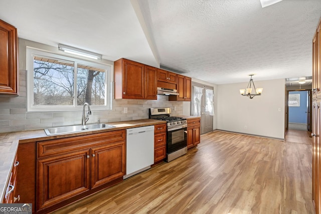 kitchen featuring sink, stainless steel gas stove, hanging light fixtures, dishwasher, and decorative backsplash