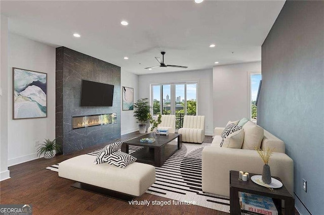 living room with ceiling fan, dark hardwood / wood-style flooring, and a tile fireplace