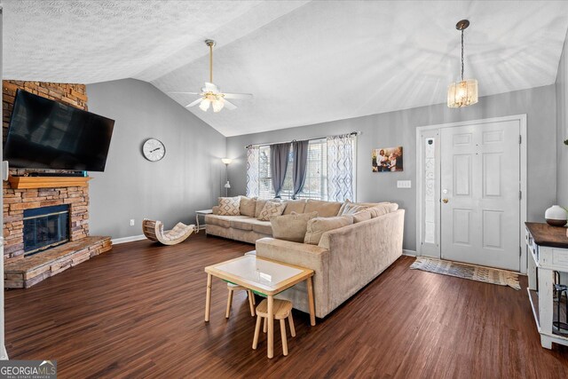 living room with ceiling fan, dark hardwood / wood-style flooring, lofted ceiling, and a stone fireplace