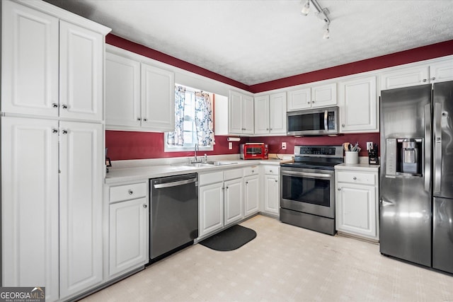 kitchen with white cabinetry, rail lighting, stainless steel appliances, a textured ceiling, and sink