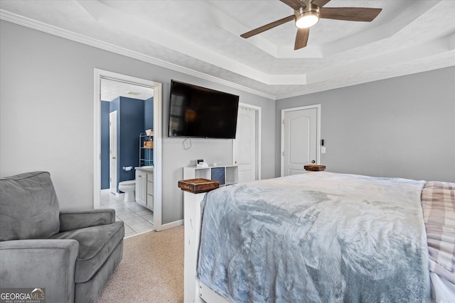 tiled bedroom with a raised ceiling, ceiling fan, ensuite bathroom, and ornamental molding