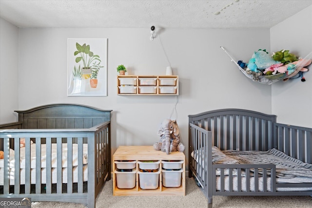 bedroom with a crib, a textured ceiling, and carpet flooring