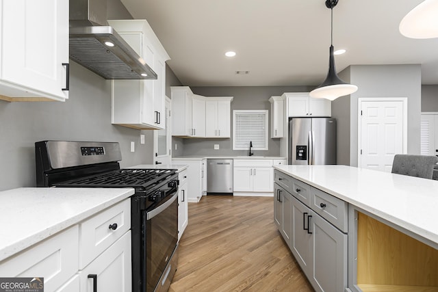 kitchen with pendant lighting, white cabinetry, stainless steel appliances, and wall chimney exhaust hood