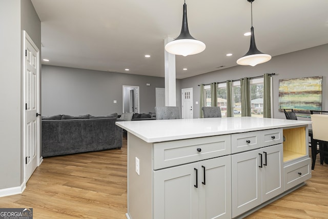 kitchen featuring white cabinetry, a kitchen island, hanging light fixtures, and light wood-type flooring