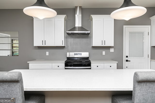 kitchen featuring white cabinetry, wall chimney range hood, stainless steel range, and decorative light fixtures