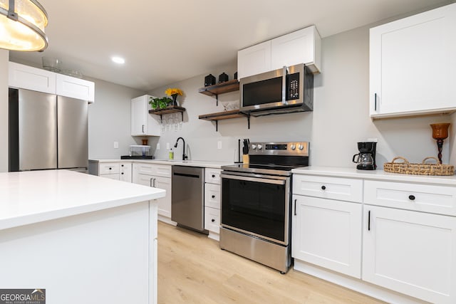 kitchen featuring pendant lighting, sink, stainless steel appliances, light hardwood / wood-style floors, and white cabinets