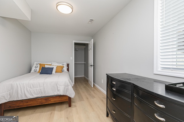 bedroom with a spacious closet and light wood-type flooring