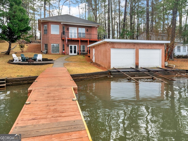 dock area featuring a water view, an outdoor fire pit, and a balcony