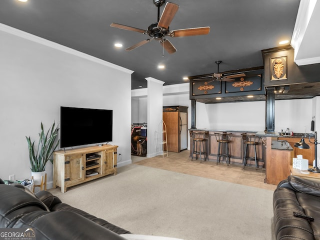 carpeted living room with ceiling fan, ornamental molding, and indoor bar