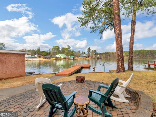 view of patio featuring an outdoor fire pit, a water view, and a dock