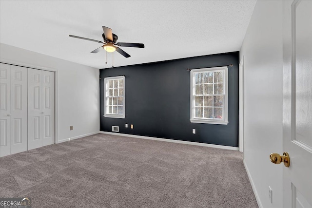 unfurnished bedroom with ceiling fan, carpet, a closet, and a textured ceiling