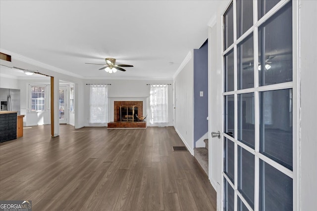 unfurnished living room featuring ceiling fan, dark hardwood / wood-style flooring, ornamental molding, and a fireplace