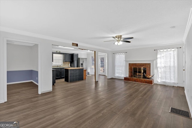 unfurnished living room featuring a healthy amount of sunlight, dark hardwood / wood-style floors, ornamental molding, and a fireplace