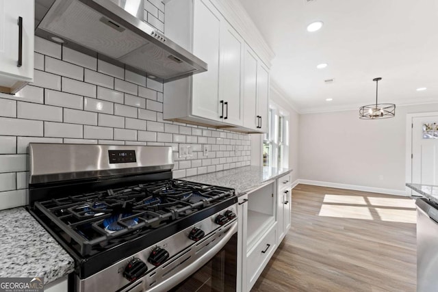 kitchen with light stone counters, white cabinets, stainless steel appliances, and wall chimney range hood