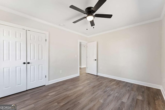 unfurnished bedroom with crown molding, ceiling fan, dark hardwood / wood-style floors, and a closet