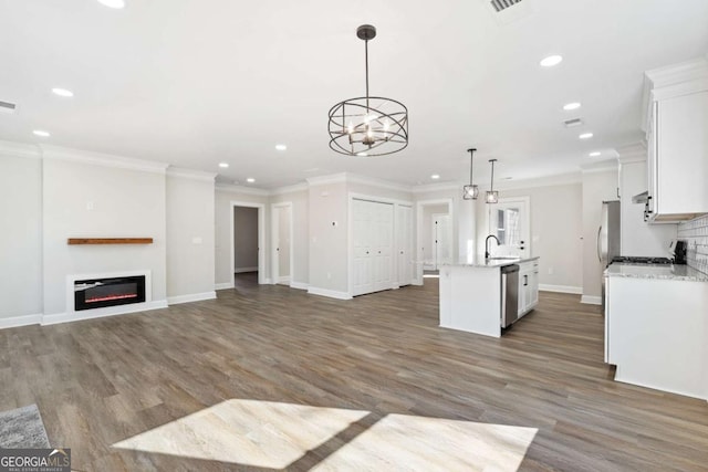 kitchen with appliances with stainless steel finishes, pendant lighting, an island with sink, white cabinets, and light stone counters