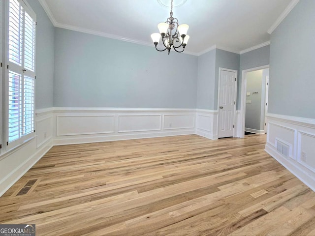 empty room with a chandelier, plenty of natural light, ornamental molding, and light hardwood / wood-style floors