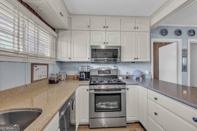 kitchen with white cabinets, light stone countertops, and stainless steel appliances