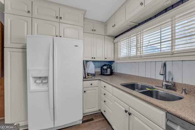 kitchen featuring wood finished floors, white cabinetry, a sink, white refrigerator with ice dispenser, and stainless steel dishwasher